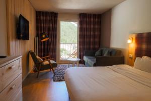 a hotel room with a bed and a couch at Hôtel Le Refuge des Sources in Digne-les-Bains