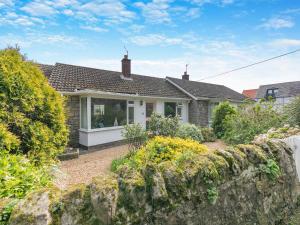 a house with a stone wall in front of it at Seashell Haven in Beadnell