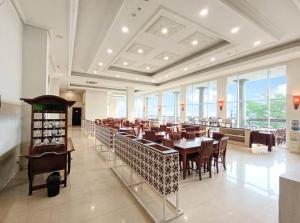 a dining room with tables and chairs and windows at Onih Hotel in Bogor