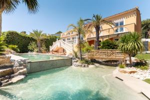 a swimming pool in front of a house with palm trees at Villa Halo Lagoon Pool & Exclusive seaside getaway in Cap d'Agde +109 photos