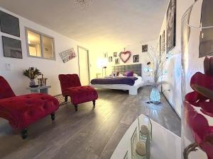 a bedroom with two red chairs and a bed at So Chic Romance au pied du Château in Sedan