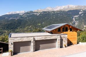 a house with two garage doors in front of a mountain at Villa moderne avec Jacuzzi - ski - golf in Icogne