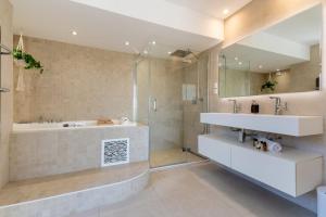 a bathroom with a tub and a sink and a shower at Villa Halo Lagoon Pool & Exclusive seaside getaway in Cap d'Agde