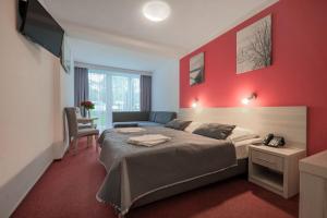 a bedroom with a bed and a red wall at Hotel *** NAT Krynica Morska in Krynica Morska +53 photos