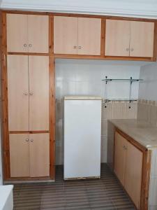 a kitchen with a white refrigerator and wooden cabinets at Appartement S2 Hammamet Centre in Hammamet