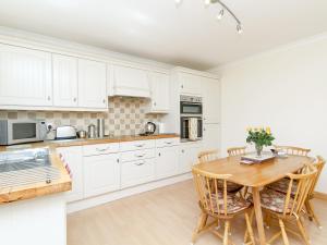 a kitchen with white cabinets and a wooden table at Ach-Na-Clachan in Gairloch