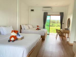a hotel room with two beds with a teddy bear sitting on top at Monanza Hotel in Ban Thung Prong +8 photos