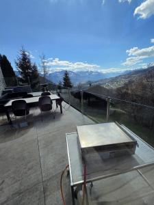 a table and chairs on a balcony with a view at Villa moderne avec Jacuzzi - ski - golf in Icogne