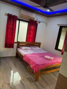 a bedroom with a bed in a room with red curtains at Serina Guest House Malvan in Malvan