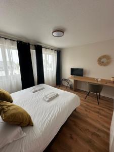 ein Schlafzimmer mit einem Bett und einem Schreibtisch mit Fernseher in der Unterkunft Hotel les Alignements in Carnac