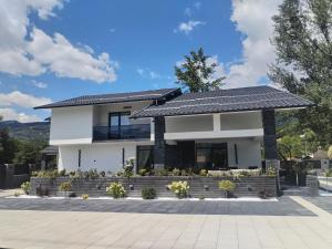 a white house with a black roof at Vila Cristal in Arefu