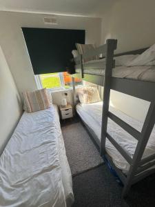 a bedroom with two bunk beds and a window at Pine Lodge @Puffin Lodges in Chwilog +32 photos