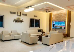 a waiting room with white chairs and a flat screen tv at Raj Royal Hotel in Nagpur