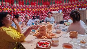 a group of people sitting around a table with food at Ак кайын in Chok-Tal