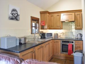a kitchen with wooden cabinets and a black counter top at River View Cottage-Uk42226 in Low Borrowbridge