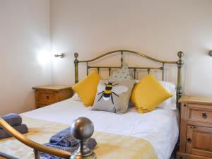 a bedroom with a bed with yellow and white pillows at River View Cottage-Uk42226 in Low Borrowbridge