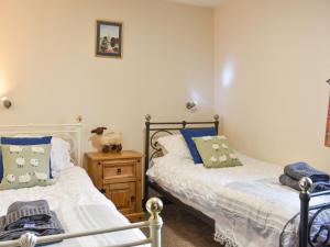 a bedroom with two beds and a wooden night stand at River View Cottage-Uk42226 in Low Borrowbridge +3 photos
