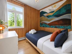 a bedroom with a bed with a painting on the wall at Chic Shack with spa - near Massif Charlevoix & MSA in Saint-Tite-des-Caps