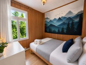 a bedroom with a bed with a painting on the wall at Chic Shack with spa - near Massif Charlevoix & MSA in Saint-Tite-des-Caps +34 photos