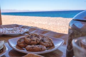 three cookies on a plate on a table near the beach at Eden Camp Abu Galum in Dahab
