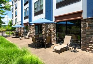 a patio with a table and chairs and umbrellas at SpringHill Suites Pittsburgh Mills in Tarentum