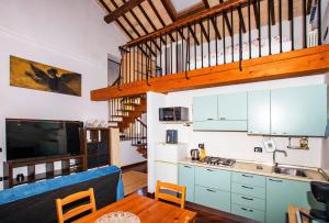 a kitchen and living room with a dining room table and a kitchen with blue cabinets at Dimora RAVENNA CORTE CHARME Diaz in Ravenna