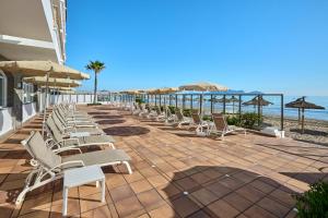 a row of lounge chairs and umbrellas on the beach at Grupotel Dunamar in Can Picafort