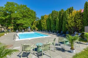 a group of chairs and a pool with trees at Apartamenty pod Modrzewiem in Ustronie Morskie