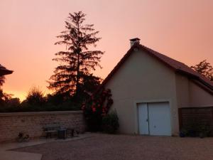 a small white building with a tree in the background at Chambres d'hôtes Arcelot in Arceau