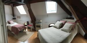 a attic bedroom with two beds and two windows at Chambres d'hôtes Arcelot in Arceau