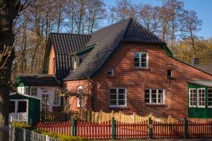 a brick house with a black roof and a fence at FeWo-Dierhagen in Prerow