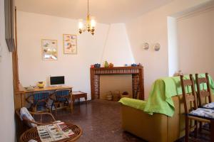 a living room with a fireplace and a desk with a computer at Casa Zolesiop in SantʼAnna Arresi