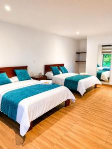 a bedroom with two beds with blue and white sheets at Hotel Takuara in Vergara +13 photos