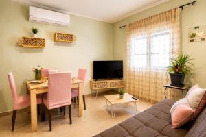 a living room with a table and a television at Goldtown House in Chrysoupolis