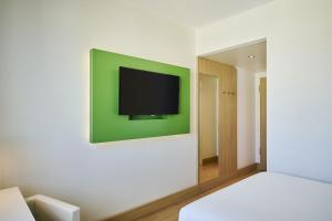 a tv on a wall in a room with a bed at NH Berlin Potsdamer Platz in Berlin