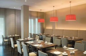 a dining room with tables and chairs and chandeliers at NH Berlin Potsdamer Platz in Berlin