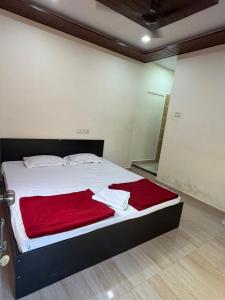 a bedroom with a bed with a red blanket on it at Serina Guest House Malvan in Malvan