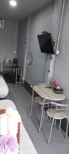 a room with a table and a tv on a wall at Khai Mook Homestay in Nan