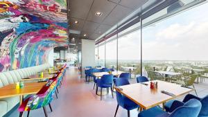 a restaurant with tables and chairs and a mural at nhow Amsterdam Rai in Amsterdam