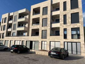 two cars parked in a parking lot in front of a building at Lastva Cozy apartment in Prijevor