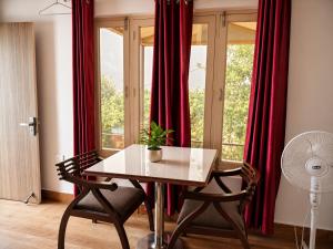 a table and chairs in a room with red curtains at Hotel Hill Top Palace in Lansdowne +41 photos