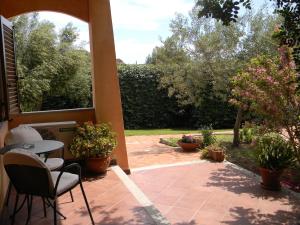 a patio with a table and chairs and plants at Relais Fenicottero Rosa in Porto San Paolo