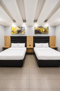 two beds in a room with paintings on the wall at Hotel Metro Lodge Beach in Durban