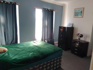 a bedroom with a green bed and a window at House near beach in Port Talbot