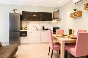 a kitchen with a wooden table and pink chairs at Goldtown House in Chrysoupolis