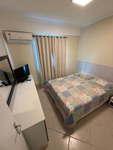 a small bedroom with a bed and a desk at Apartamento Elizabetta 3, pé na areia in Arraial do Cabo