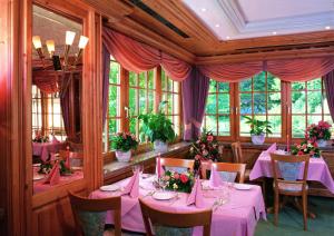 a dining room with pink tables and chairs and windows at Schwarzwaldhotel Klumpp in Baiersbronn