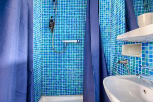 a blue tiled bathroom with a shower and a sink at Le Bretagne - Hôtel de charme labellisé Cosy Places in Vannes +46 photos