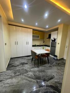 a kitchen with a table and a kitchen with white cabinets at Peev Apartements in Abuja