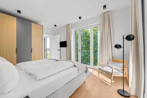a white bedroom with a large bed and a chair at Ferienwohnung Seaside App 9 List auf Sylt in List